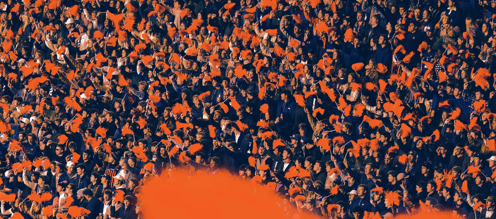 Auburn fans waving orange pom-poms in the stands at Jordan-Hare Stadium